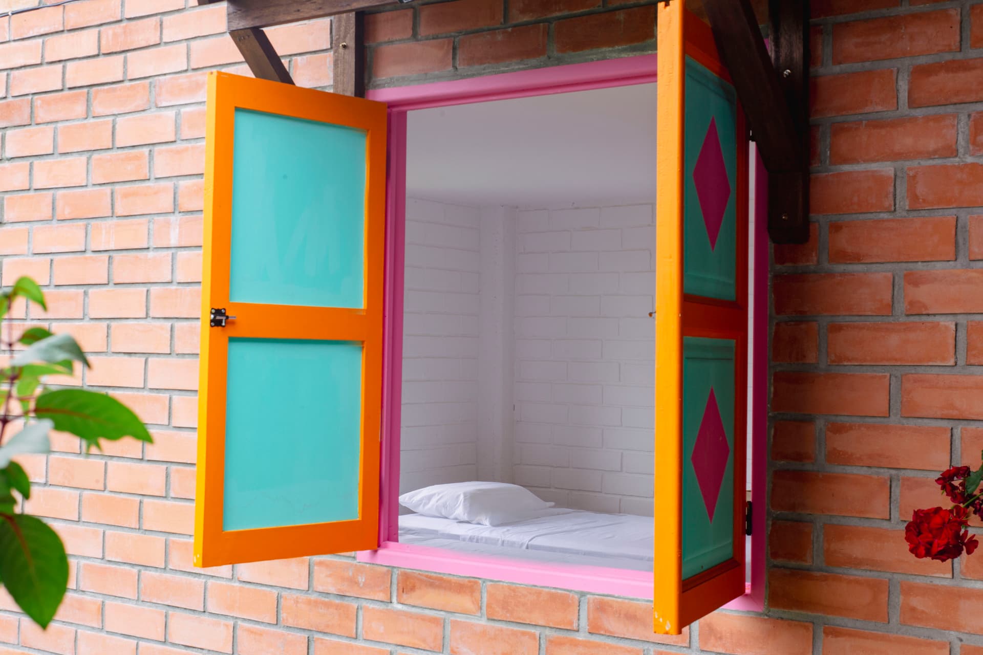 Freelance designer working on a laptop at Isla de Pascua hostel in Jardín with colorful buildings visible through the window